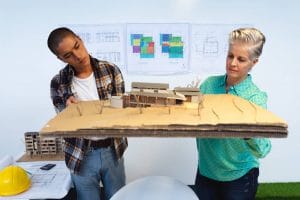 2 people holding a model of a house