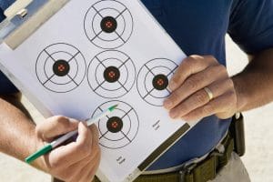 A mid body shot of a man holding circular targets drawn on paper