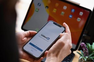 A mobile phone being held showing the LinkedIn mobile app