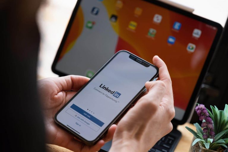 A mobile phone being held showing the LinkedIn mobile app